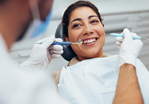 a smiling woman having her teeth examined at the dentist’s office