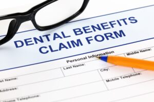 Closeup of a dental benefits claim form with pen and glasses